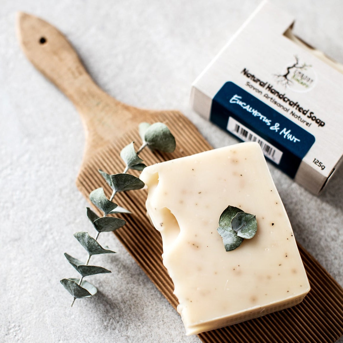 Eucalyptus Mint Soap Bar by Embody Nature is out of the box, sitting on a wood board.  
